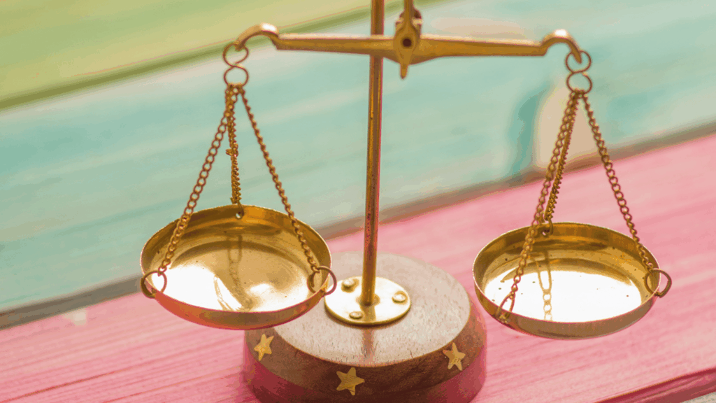 A gold balance scale on a multicolored table.