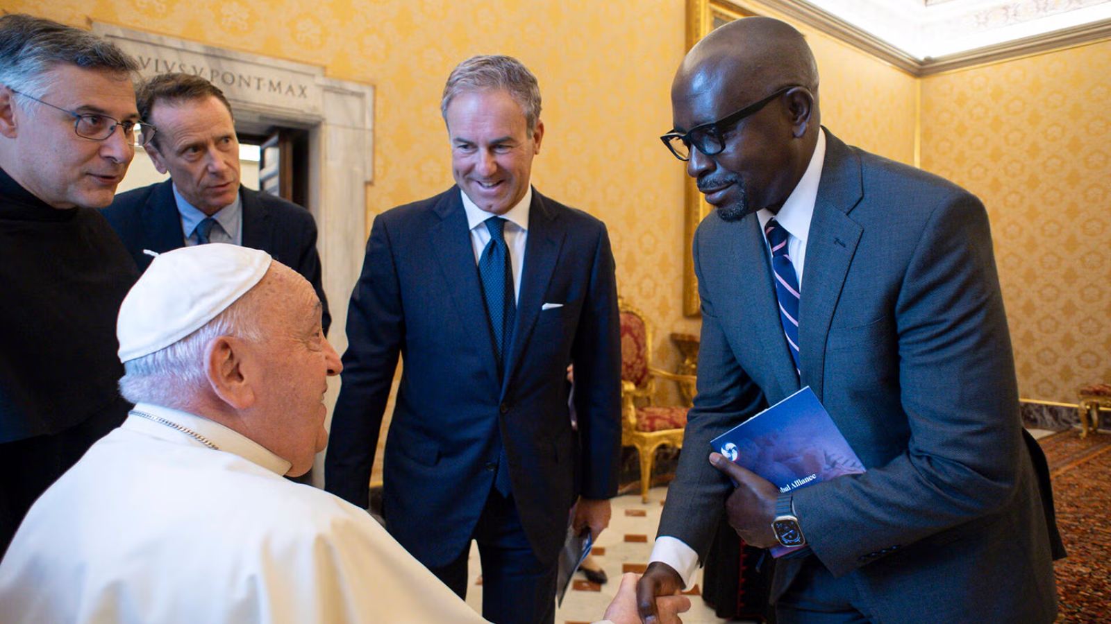 Pope Francis shaking hands with Deus Bazira.