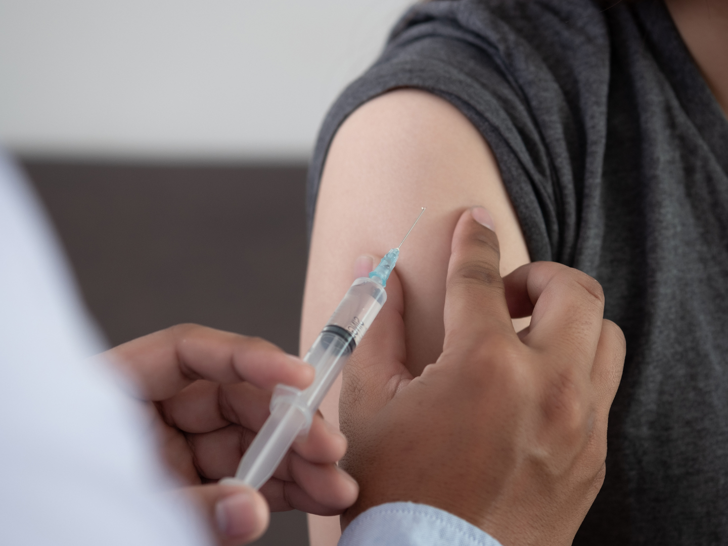 A closeup shot of a doctor injecting vaccine on an arm.