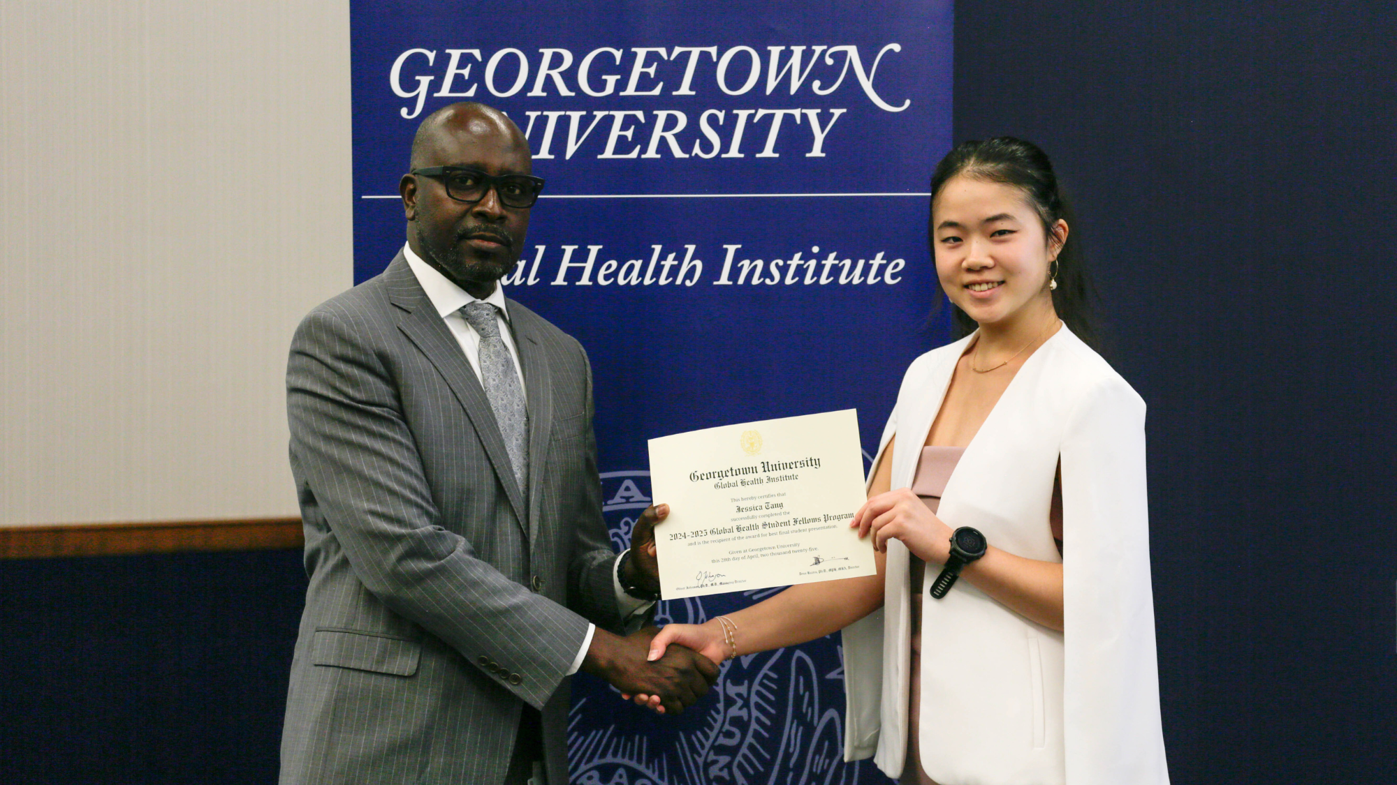 Deus Bazira shaking hands and giving a certificate to student fellow Jessica Tang.