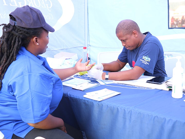 A man giving a woman a blood sugar prick test.