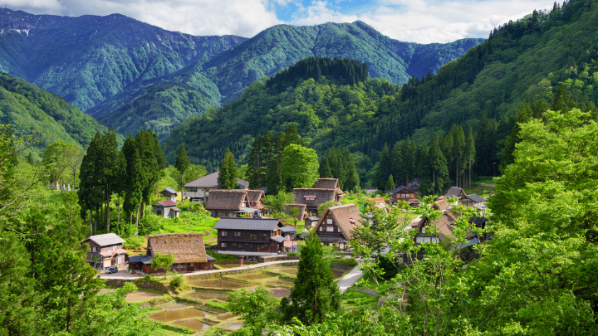 A traditional village surrounded by trees and mountains.