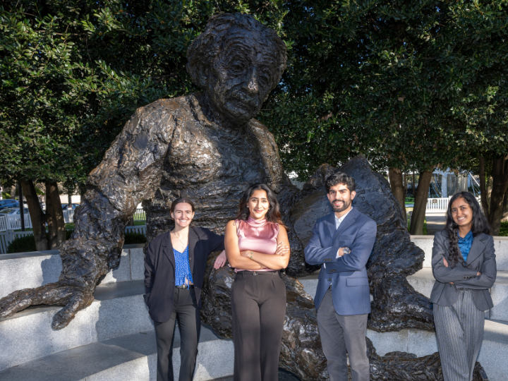 People posed in front of an Albert Einstein statue.